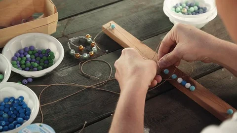 Close-up of female hands stringing beads on a thread, making a jewelry bracelet Stock Footage 119647853