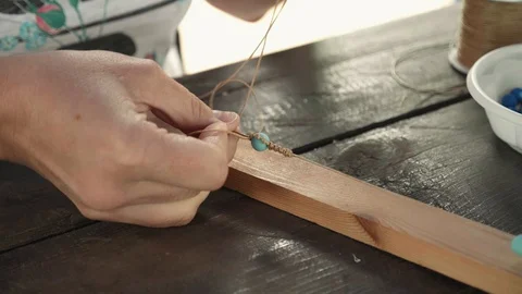 Close-up of female hands stringing beads on a thread, making a jewelry bracelet Stock Footage 119648912