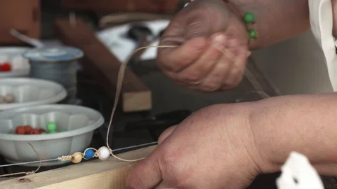 Close-up of female hands stringing beads on a thread, making a jewelry bracelet Stock Footage 119649124
