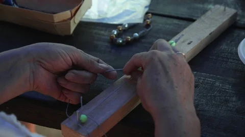Close-up of female hands stringing beads on a thread, making a jewelry bracelet Stock Footage 119649245