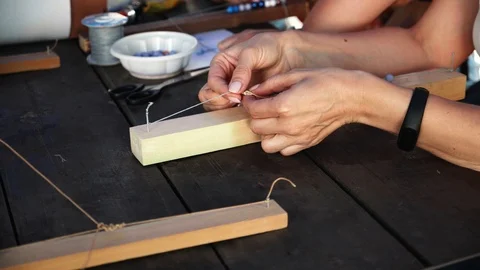 Close-up of female hands stringing beads on a thread, making a jewelry bracelet Stock Footage 119649349