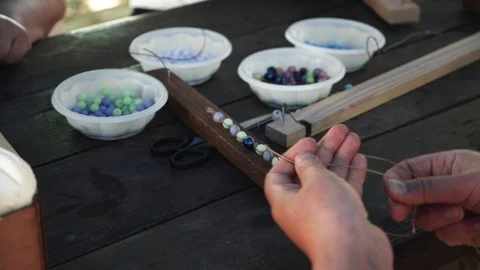Close-up of female hands stringing beads on a thread, making a jewelry bracelet Stock Footage 119649415