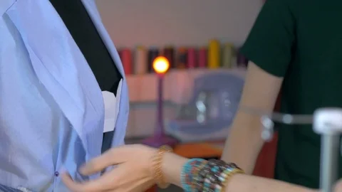 Close-up of female hands tailoring a jacket on model in small creative office. Stock Footage 80471666