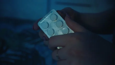Close-up of female hands take a white pill out of the plate at night in kitchen Stock Footage 247920064