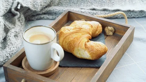 Close up of female hands taking cup with coffee and croissant from tray Stock Footage 122987798