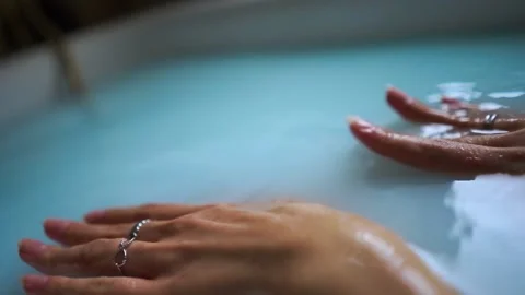 Close-up of female hands touching the surface of the water in a bath with a milk Stock-Footage 137127136