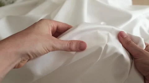 Close up of female hands touching white cotton satin fabric. Inspecting textile. 库存影片 318482458