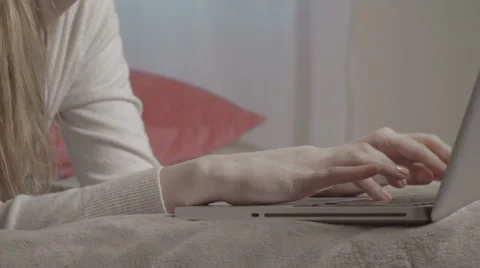 Close up of female hands typing on computer while lying on bed. Stockbeeldmateriaal 61674182
