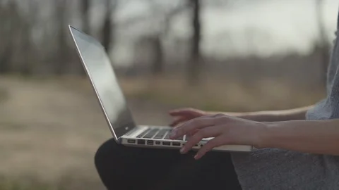 Close up of female hands typing on computer in a park. Vidéo 129256667