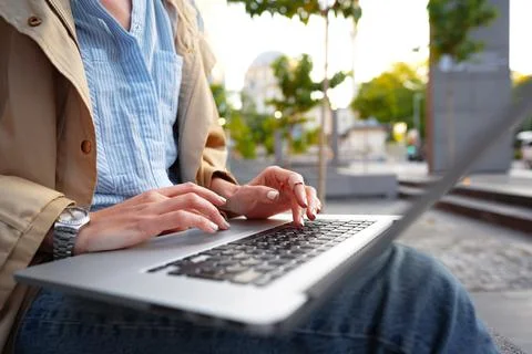 Close up of female hands typing on computer keyboard of a laptop sitting in the Stock Photos