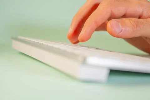 Close up of female hands typing on computer keyboard on light green backgroun Stock Photos