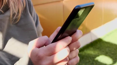 Close-up female hands typing on a smartphone outdoors on a sunny terrace Stock Footage 321808642