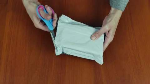 Close-up female hands unpack a plastic package from a postal parcel with 動画素材 220243044