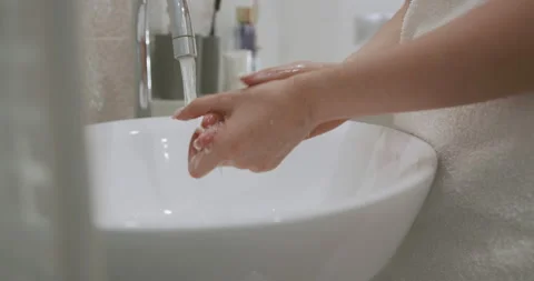 Close up of female hands using antibacterial soap while washing hands at Stock Footage 147507717