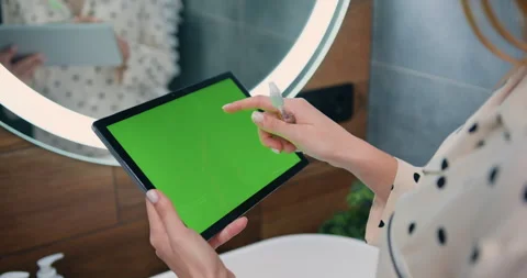 Close-up of female hands using black tablet with green screen on bathroom at Video stock 241508810