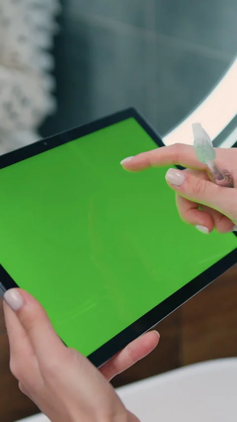 Close-up of female hands using black tablet with green screen on bathroom at hom Stock Footage 334477348