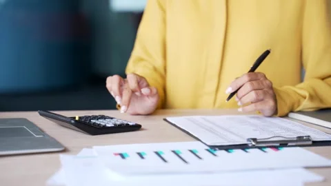 Close-up of female hands using calculator and writing notes at desk in modern  Stock Footage 328219368