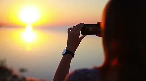 Close-up of female hands using the camera on the phone to photograph the sunset Stock Footage 68821116