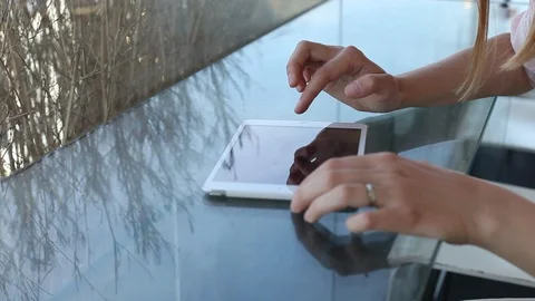 Close up of female hands using digital tablet on glass table in cafe Stock Footage 98099576