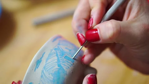 Close-up of female hands using metal rod for engraving of a clay ceramic bowl Stock Footage 256325297