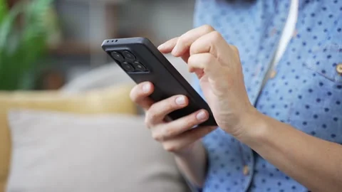 Close up of female hands using mobile phone in modern living room. Young woman  Stock Footage 320415198