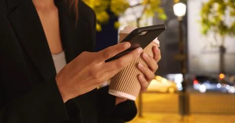 Close up of female hands using mobile phone to text message at night in Paris 写真素材