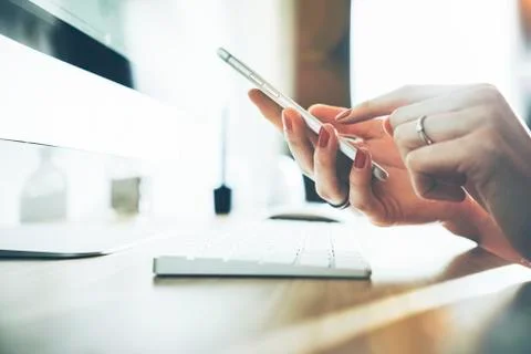 Close-up of female hands using modern smart phone while working at office Stock Photos