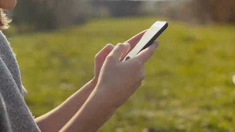 Close up of female hands using a smart phone in a park. 動画素材 129255068
