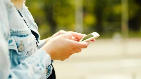 Close up of female hands using a smart phone in a city park. Foto stock
