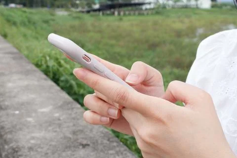 Close up of female hand's using the smartphone at the outdoor. Stock Photos