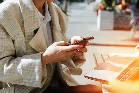 Close-up of female hands using smartphone in street cafe. Business woman fr.. 写真素材