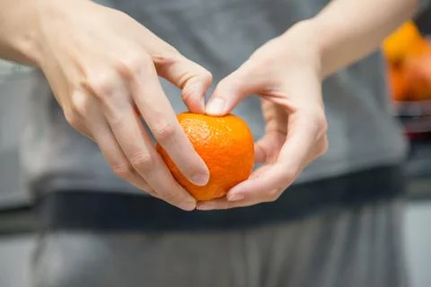 Close up of female hands which are cleaning mandarin. Selective focus Stock Photos
