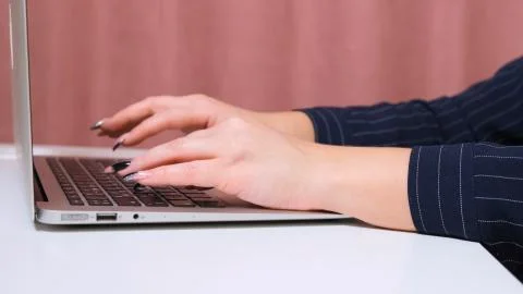 Close up of female hands while typing on laptop. Stock Photos