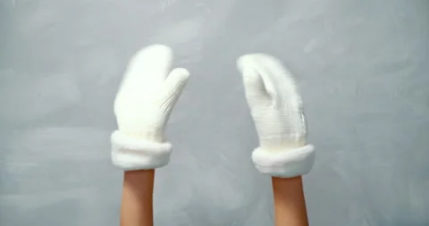 Close up female hands in white woolen mittens waving on a gray background. Stock Footage 132584548