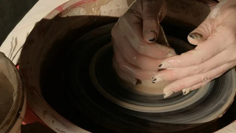 Close-up female hands working with raw clay on pottery wheel Видео 101702640