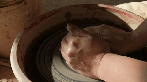 Close-up female hands working with raw clay on pottery wheel Видео 101702664