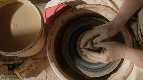 Close-up female hands working with raw clay on pottery wheel Видео 101702726