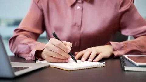 Close-up of female hands writing in notebook at office desk. Businesswoman  库存影片 332850883