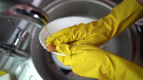Close up of female hands in yellow protective rubber gloves washing white plate  Stock Footage 128424512