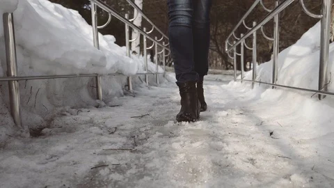 Close-up female legs walking down the street in almost melted snow. Spring on th Video stock 105225402