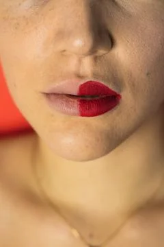 Close up of female lips with two different lipsticks. Red background Stock Photos