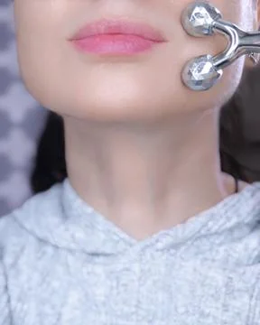 Close up of female lower face using a silver 3D manual massaging roller on .. Fotos Stock