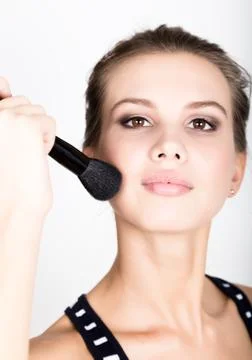Close-up Female model applying makeup on her face. Beautiful young woman Stock Photos