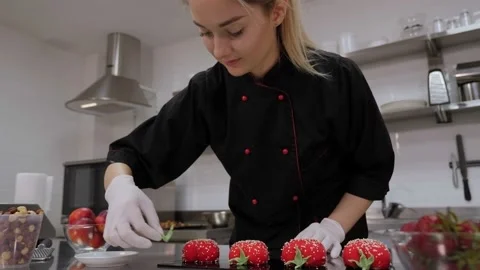 Close-up of a female pastry chef decorating mousse cakes with red mirror glaze. Stock Footage 136834105