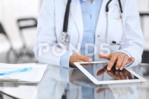 Close-up of female physician hands using digital tablet while sitting at glas Stock Photos