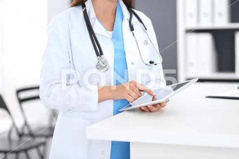 Close-up of female physician using digital tablet while standing near receptio Stock Photos