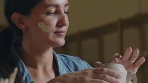 Close up of female potter using tools to making ceramic clay bottom of cup in Stock Footage 143617655