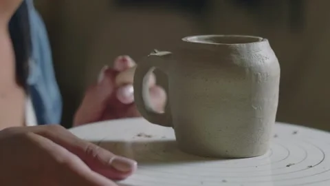 Close up of female potter using tools to making ceramic clay handle of cup in Stock Footage 143617676