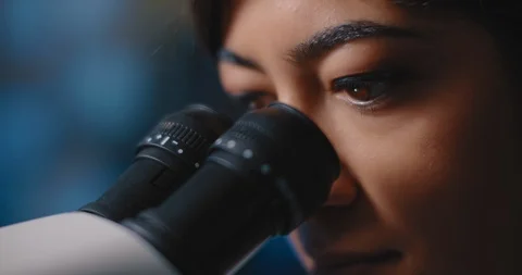 Close up of a female research scientist eyes,looking at samples under microscope Stock Footage