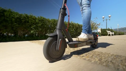 Close up - Female riding electric scooter through marina. Modern transportation Stock Footage